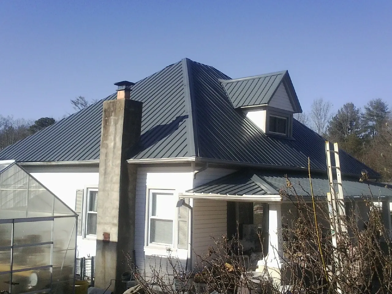 Dark blue standing seam metal roof on a white farmhouse with dormer — Slate & Tile Roof Repair by Roofing Brothers in Factoryville