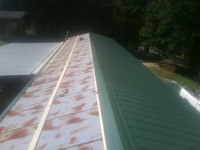 Old rusted panels beside newly installed green metal roofing — Wind Damage Roof Repair by Roofing Brothers in Factoryville