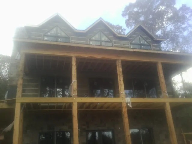Dormers and porch framing on a large log home under construction — Roof Coating work by our crew in Factoryville