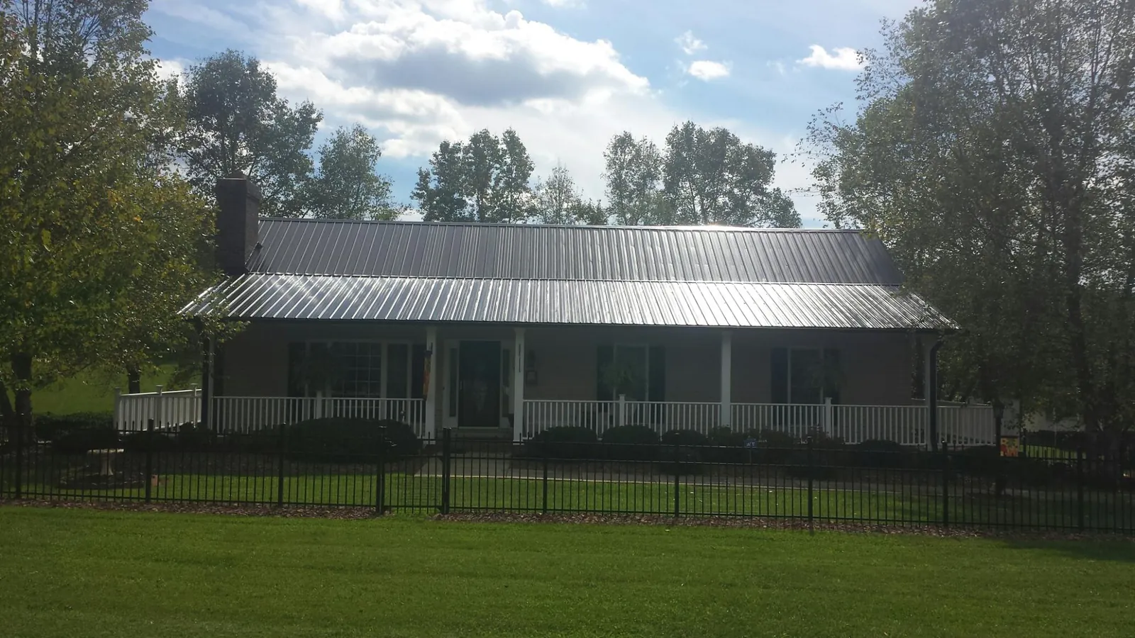 Gray metal roof on a brick ranch with a full width front porch — Gutter Guard Installation work by our crew in Factoryville