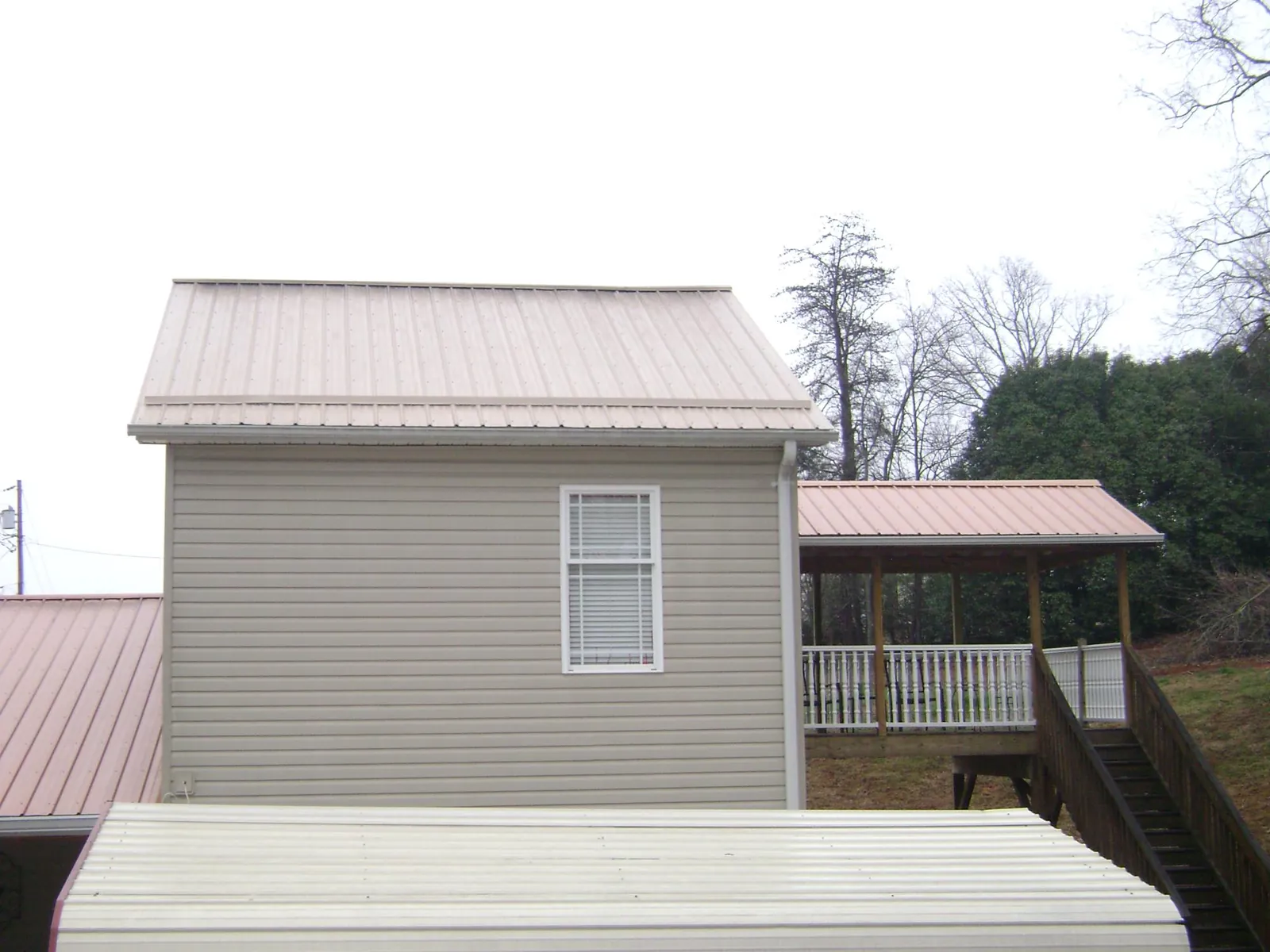 Tan metal roofs on a two story addition and attached porch, from a Roof Replacement job in Factoryville