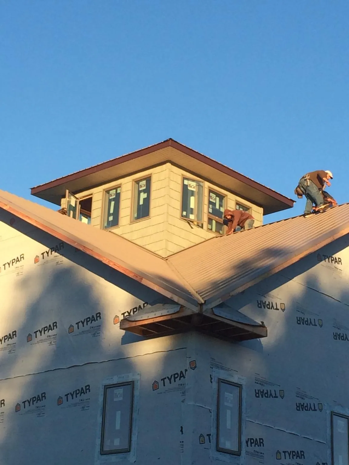 Roofers working around a rooftop cupola on a new metal roof at sunset — Roof Waterproofing in Factoryville by Roofing Brothers